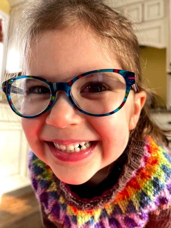 a little girl with a huge smile models her new hand knitted sweater